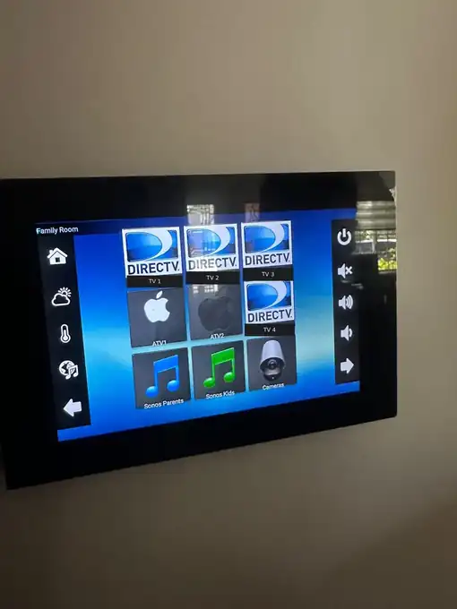 Wall-mounted RTI touch panel on a Family Room page with buttons for four DIRECTV receivers, two Apple TVs, two Sonos zones and cameras